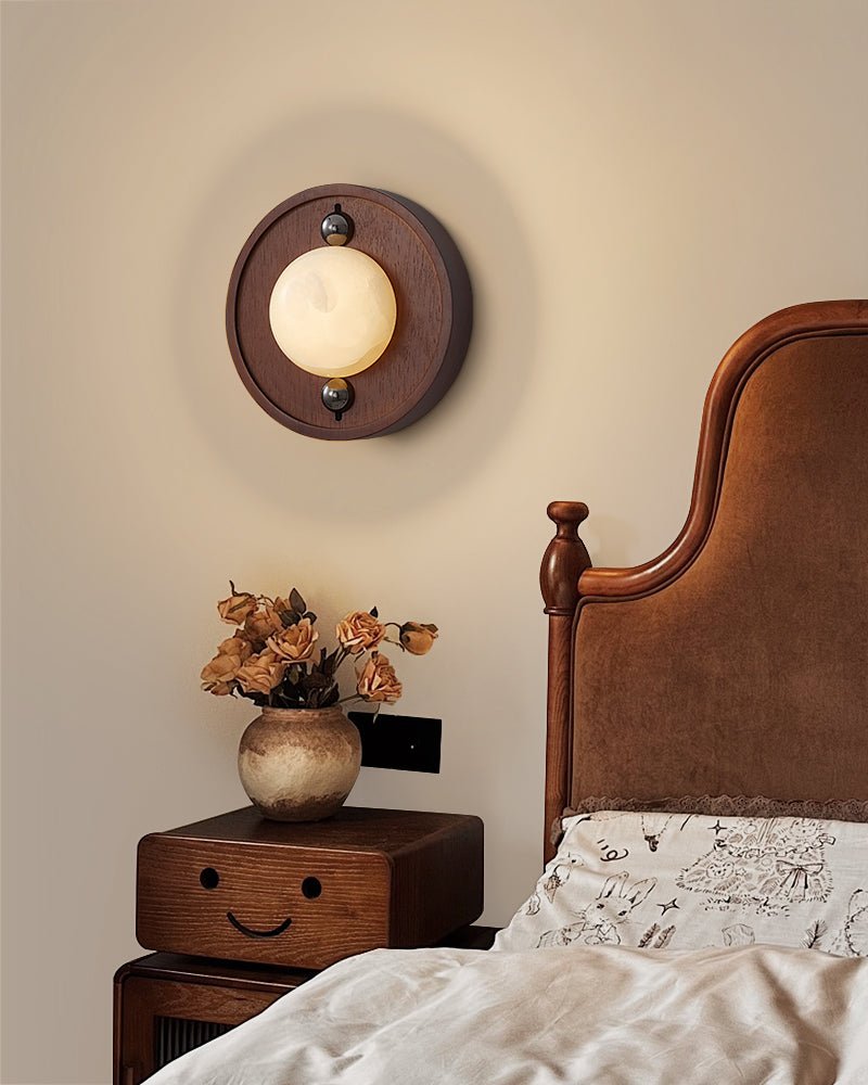 Round plate version lit above a nightstand of dried flowers beside a bed