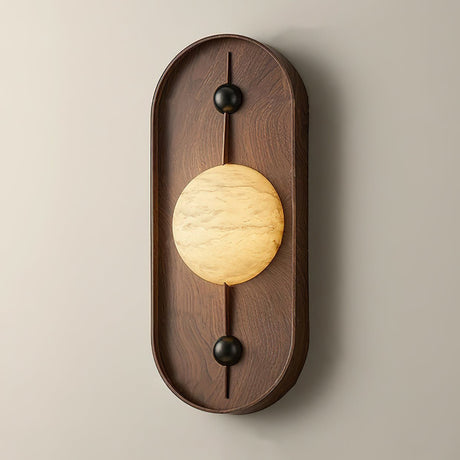 The tall walnut pill seen from the front, the veined disc lit across its middle
