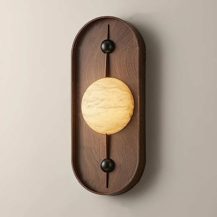 The tall walnut pill seen from the front, the veined disc lit across its middle