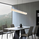 The lit bar above a dining table with chairs and a window onto the hills