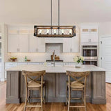 Lit above a gray kitchen island with two wood stools in a white kitchen