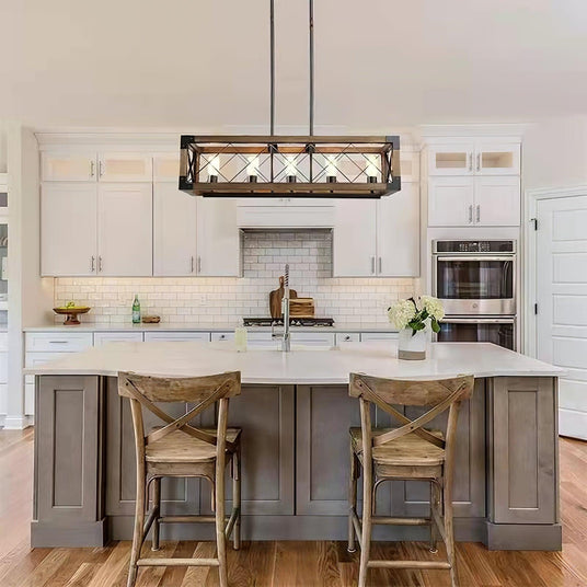 Lit above a gray kitchen island with two wood stools in a white kitchen