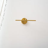 The gold rod lit from its disc mount, the beam spreading along the wall