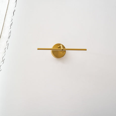 The gold rod lit from its disc mount, the beam spreading along the wall