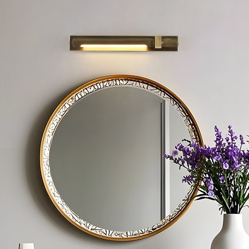 Bronze bar lit above a beaded round mirror with lavender in a white vase