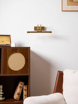 Brass bar lit above a shelf over a walnut cabinet with cane doors and an armchair