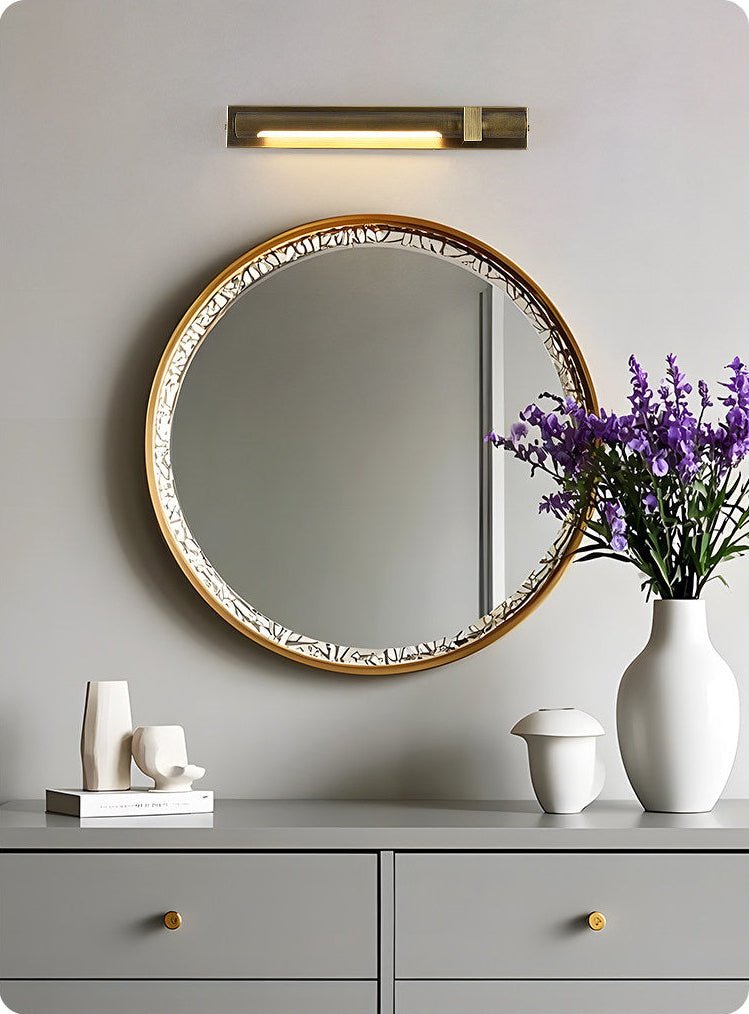 Bronze bar above a beaded mirror on a gray console with vases and books