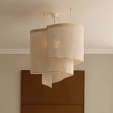 Oversized ceiling light in overlapping beige fabric shades above a sideboard