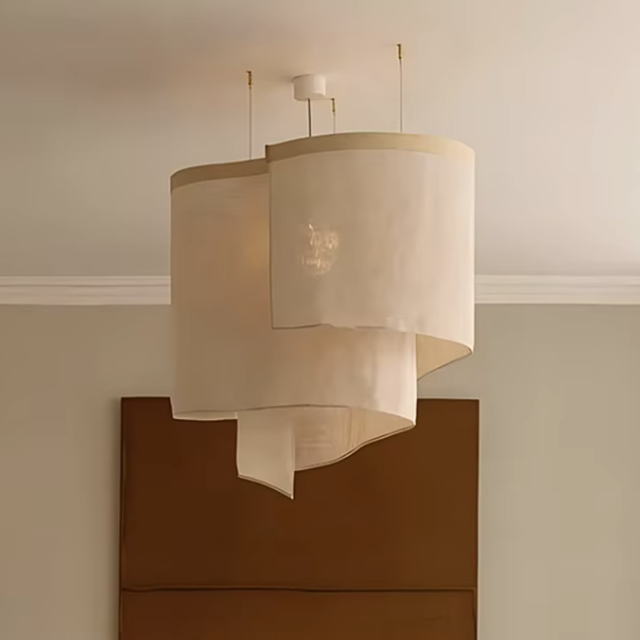 Oversized ceiling light in overlapping beige fabric shades above a sideboard