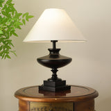 Black oversized table lamp lit on a round table in the evening