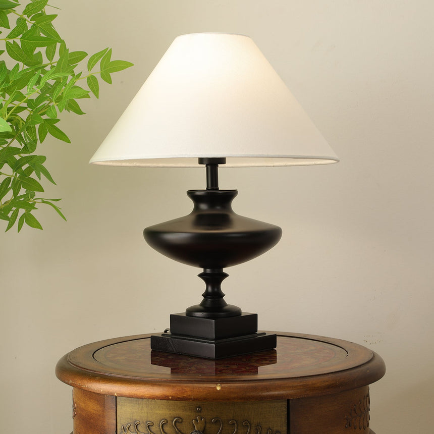 Black oversized table lamp lit on a round table in the evening
