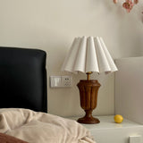 Urn base lamp lit on a nightstand beside a dark leather headboard