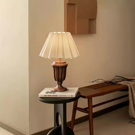 Urn base lamp lit on a small round table beside a wood bench