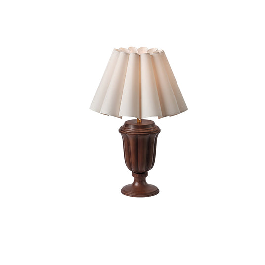 Walnut urn base lamp seen from an angle with the scalloped shade top