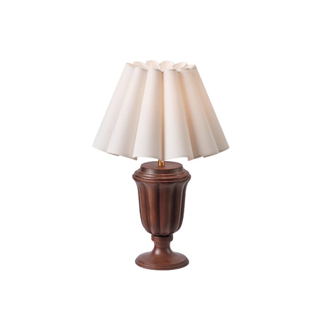Walnut urn base lamp lit, the pleated shade glowing evenly