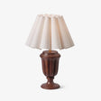 Carved urn base lamp in a walnut tone on a plain white ground