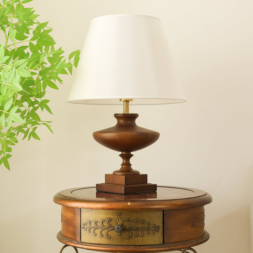 Close view of the lit white empire shade above the walnut urn base