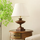 Walnut oversized table lamp seen from the side on a round wooden table