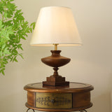 Close view of the turned walnut urn body on its stepped square plinth