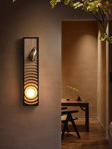Sconce lit beside an open doorway with a wood desk and chair in the room beyond
