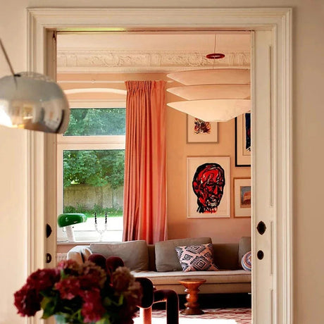 Layered paper shade above a table in a red walled room