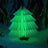 Green folding paper tree lamp lit against a dark winter background