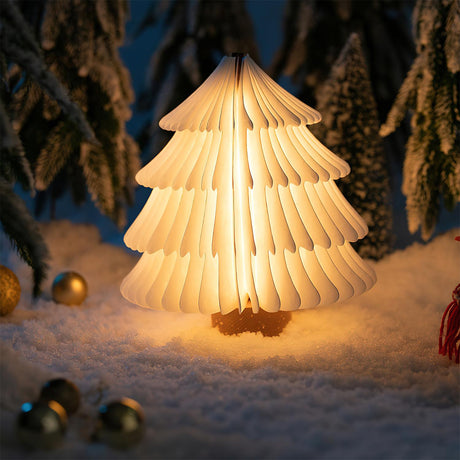 White paper tree lamp lit in a table setting with fake snow and pine