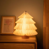 White paper tree lamp lit on a wood dresser beside a framed drawing