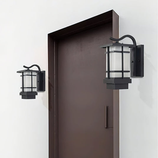 Two lanterns on a white wall on either side of a tall dark brown door
