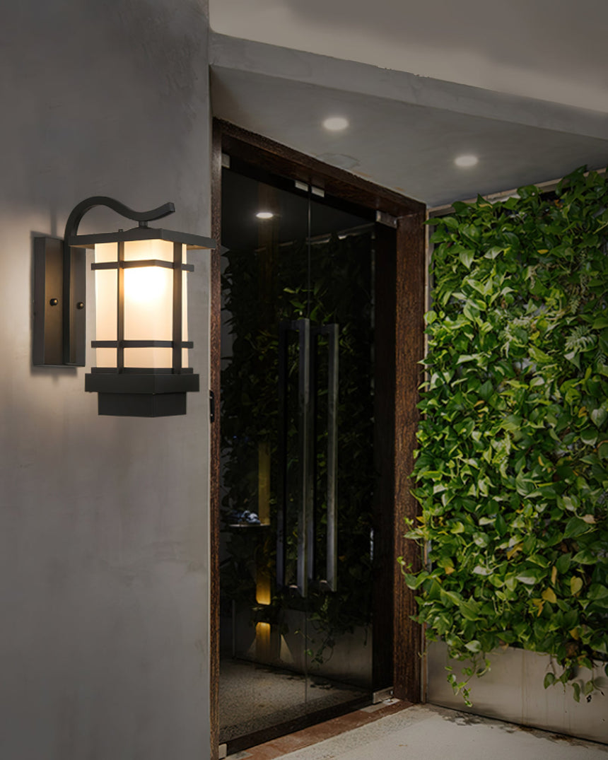 The lantern lit beside a glass entry door, a green planted wall to the right