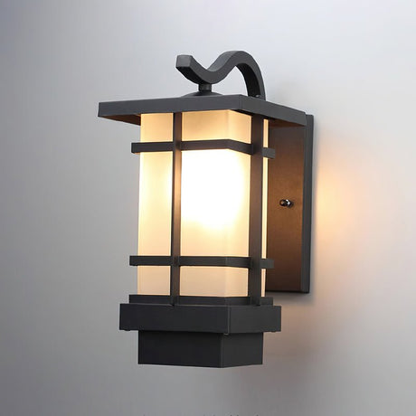 Front view of the lit lantern on a gray wall, the bars crossing the glow