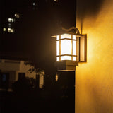 The lantern lit at night on a wall, its glow warm against the dark