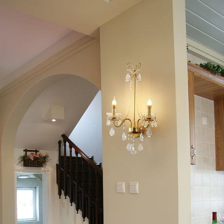 The pearl sconce lit on a column beside an arched opening and a staircase