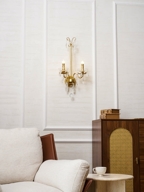 The pearl sconce on a white paneled wall above an armchair and a cane cabinet
