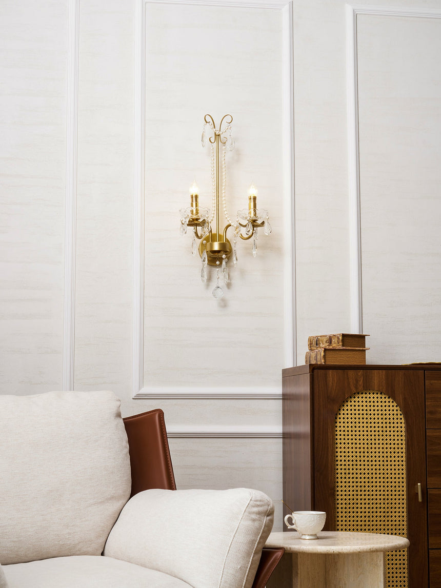 The pearl sconce on a white paneled wall above an armchair and a cane cabinet