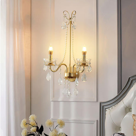 The pearl sconce lit beside a tufted headboard and a sheer curtain