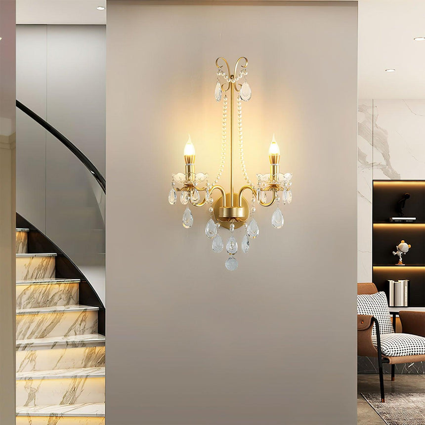The pearl sconce lit on a wall beside a curved marble staircase
