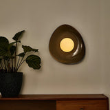 The large pebble light lit above a sideboard beside a leafy plant