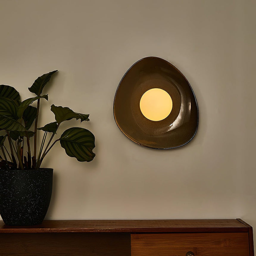 The large pebble light lit above a sideboard beside a leafy plant