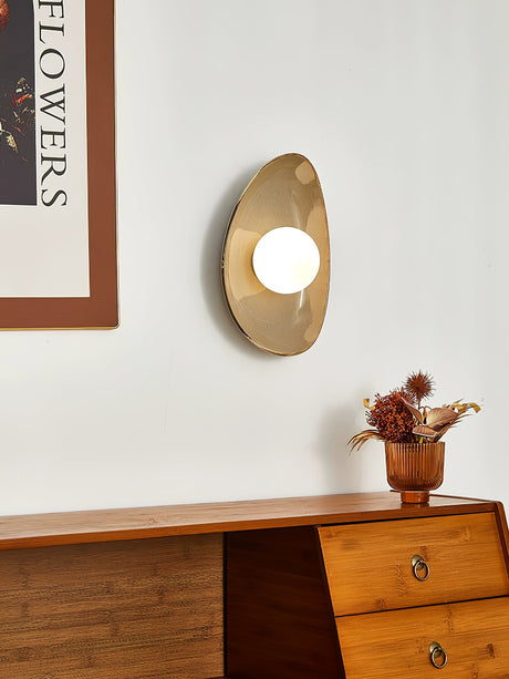 The small pebble light lit above a dresser with a small vase of dried flowers