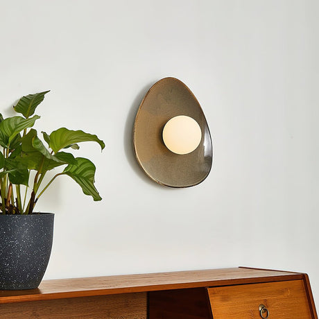 The small pebble light above a sideboard and a plant in a stone pot