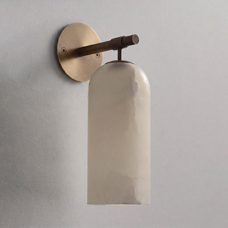 The antique bronze version with its stone cylinder, seen against a plain wall
