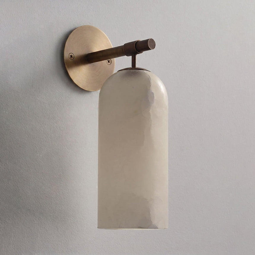 The antique bronze version with its stone cylinder, seen against a plain wall