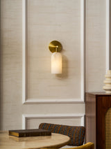 The sconce on a paneled wall above a dining table with a cup and a chair