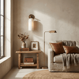 The sconce above a sofa beside a side table with books and a plant