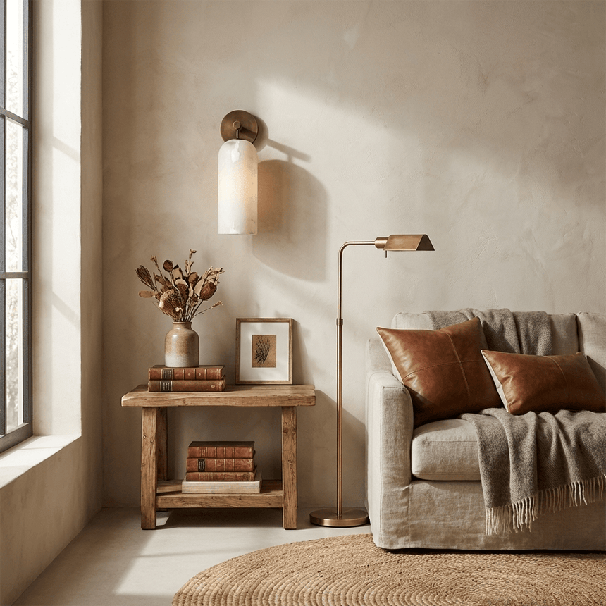 The sconce above a sofa beside a side table with books and a plant