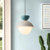 A capped opal globe lit beside a bed above a wooden shelf