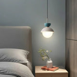 A capped opal globe lit beside a bed under a framed artwork