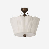 Pleated ceiling light with a beige scalloped fabric shade on a dark brown base