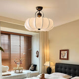 Pleated silk ceiling light lit in a bedroom with wood blinds and a black sofa